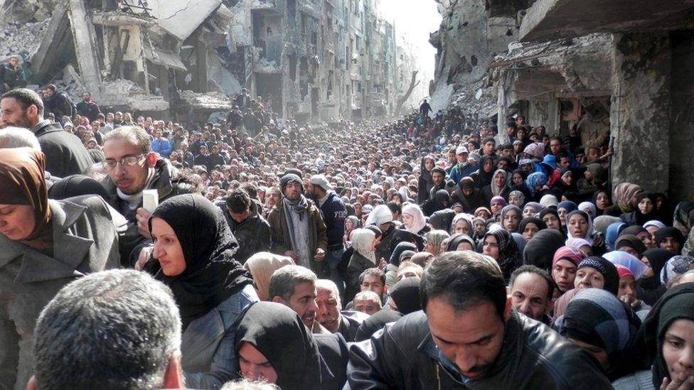 Residents of the Palestinian camp of Yarmouk, queuing to receive food supplies, in Damascus