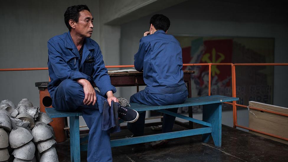 Workers sit on a bench during a media tour of the March 26 Electric Cable Factory in Pyongyang on May 6, 2016