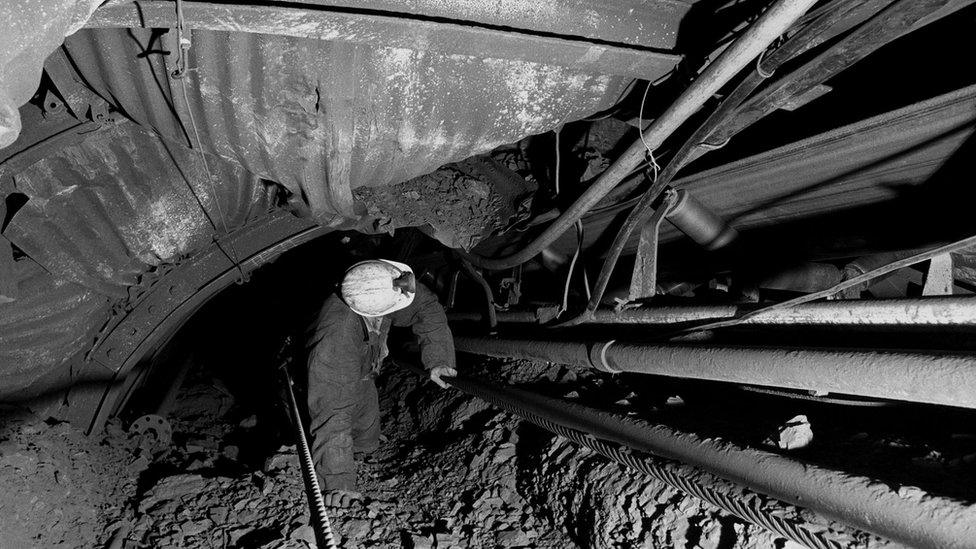 A pit official at Sutton Colliery near Mansfield, Nottinghamshire, checks on a trunk conveyor at the coal face.