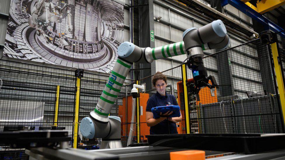 Woman and robot-arm, with scientific background.