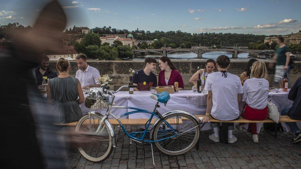 A couple sit at a table on the Charles Bridge in Prague