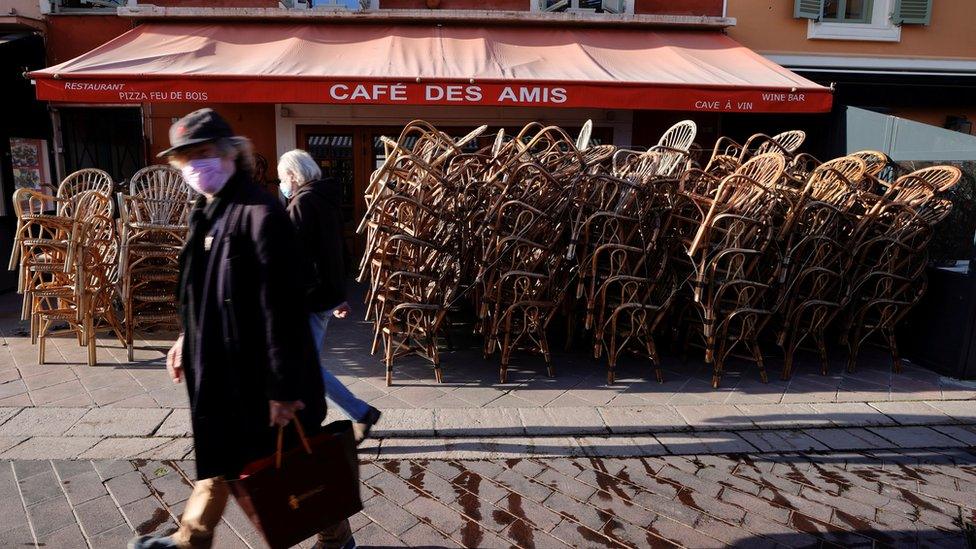 France lockdown - people walking by closed restaurant in Paris