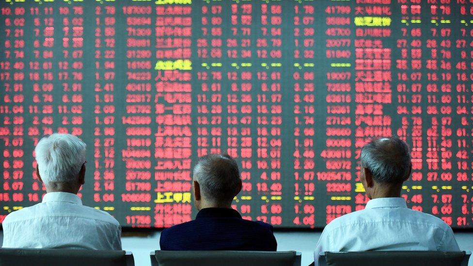 Chinese investors sit in front of a stock board