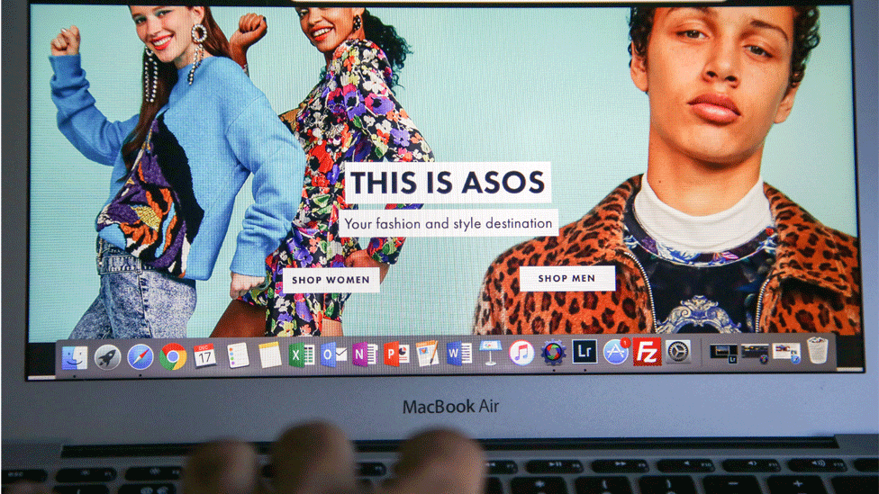 The ASOS home page open on a laptop with a woman scrolling