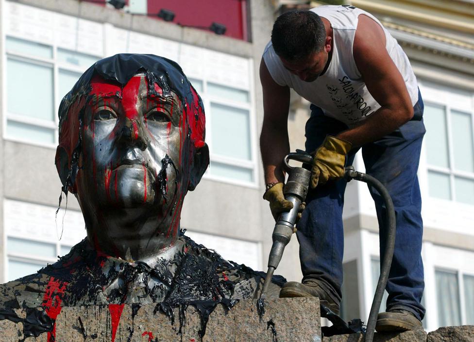 A worker frees with a drill a bust of Spanish dictator Francisco Franco (1892-1975) from its plinth prior its removal in the central square of the Spanish northwestern village of Ponteareas, 08 July 2003 following a decision by the village council.