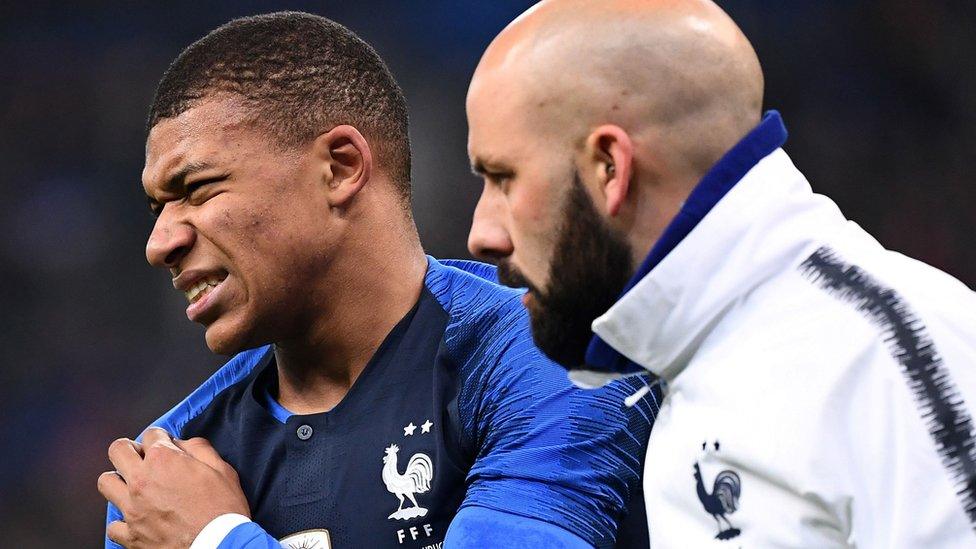 Mbappe holding his shoulder with a medic.