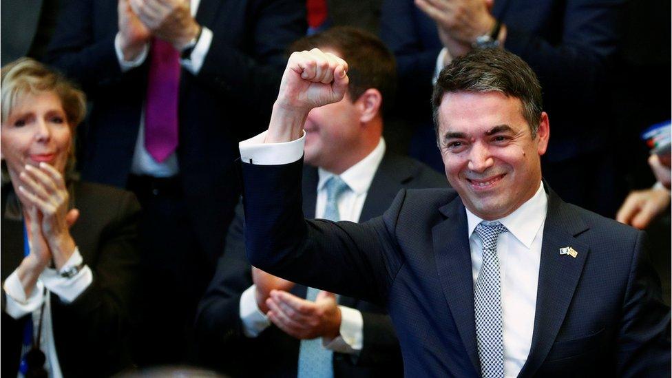 Macedonian Foreign Minister Nikola Dimitrov raises his fist during a signature ceremony of the accession protocol