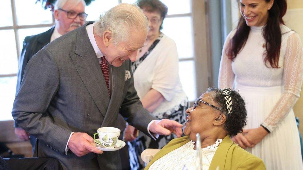 King Charles meeting Edna Henry who is sitting down while he stands