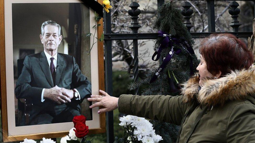 A Romanian woman closes her eyes while touching King Michael's portrait