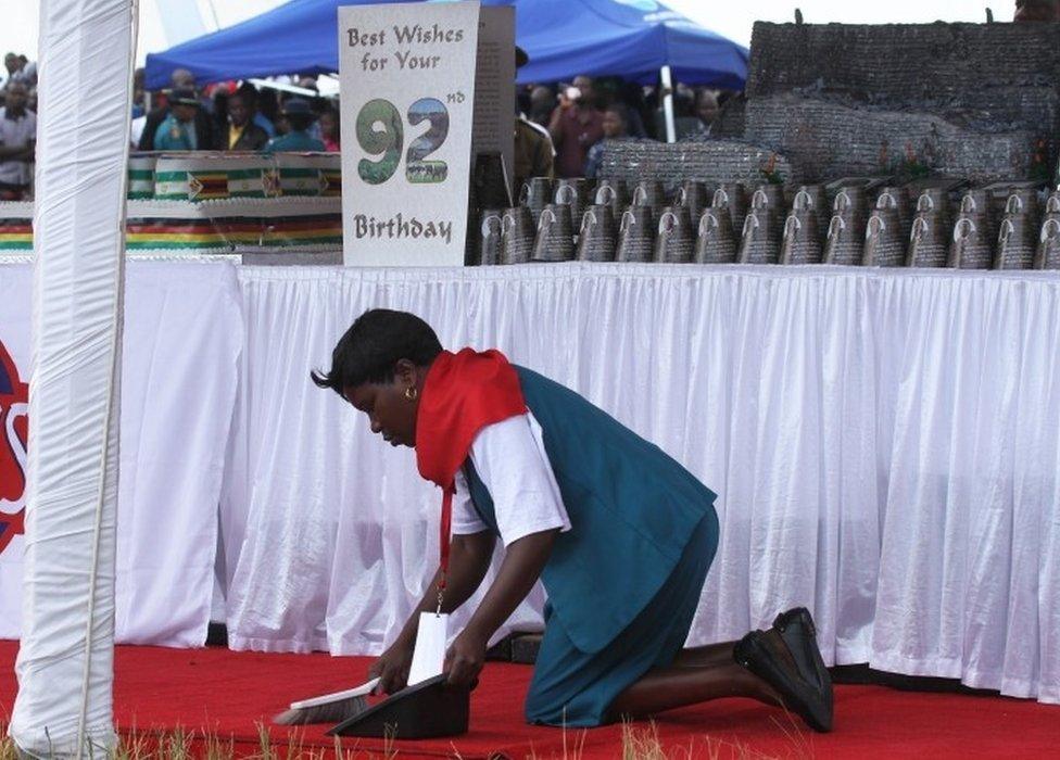 A woman cleans the carpet during celebrations for Zimbabwean President Robert Mugabe"s 92nd birthday, in Masvingo about 300 kilometres south of Harare, Saturday, Feb, 27, 2016. Called “dear father,” “his royal highness,” and “the Moses of Africa” members of the Zimbabwe’s ruling party used President Robert Mugabe’s birthday celebrations to reassert their loyalty to the longtime leader amid political infighting