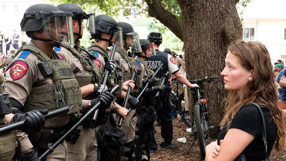 A student stares at a row of Texas State Troopers during the protests at the University of Texas