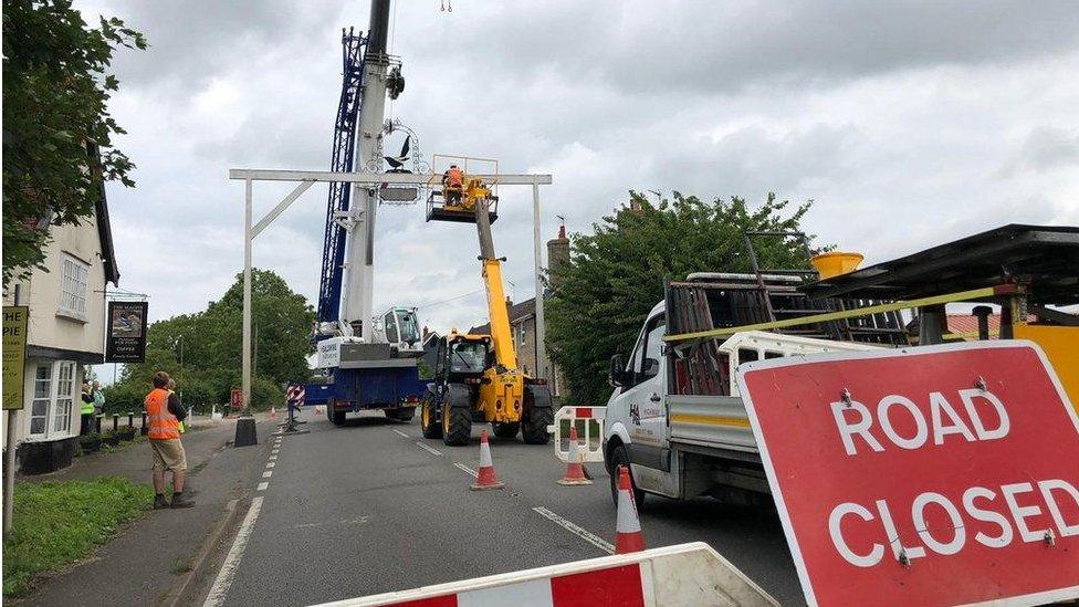 Workers use a crane to remove the damaged Magpie pub's sign at Little Stonham, Suffolk