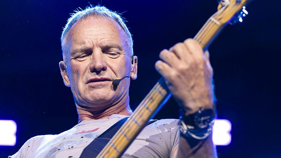 Close up of Sting playing the guitar on stage