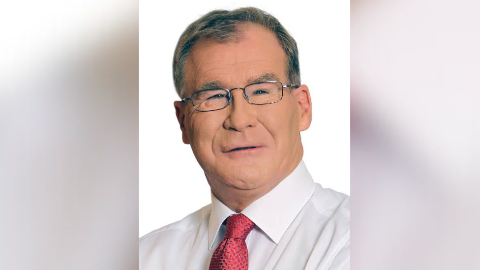 Colm Burke in a white shirt and red tie with black glasses