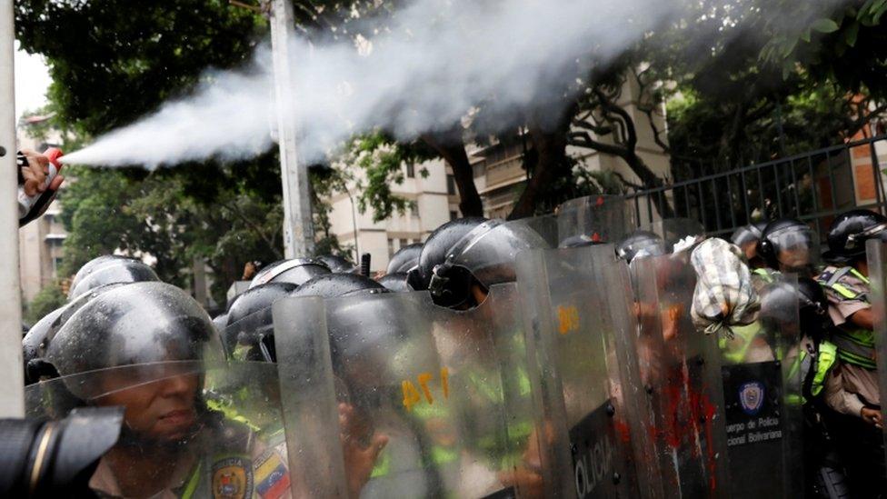 Police officer uses pepper spray at march in Caracas