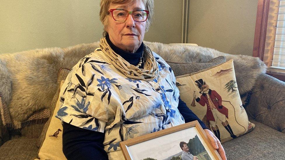 Rosemary Manns holding a photo of Thomas