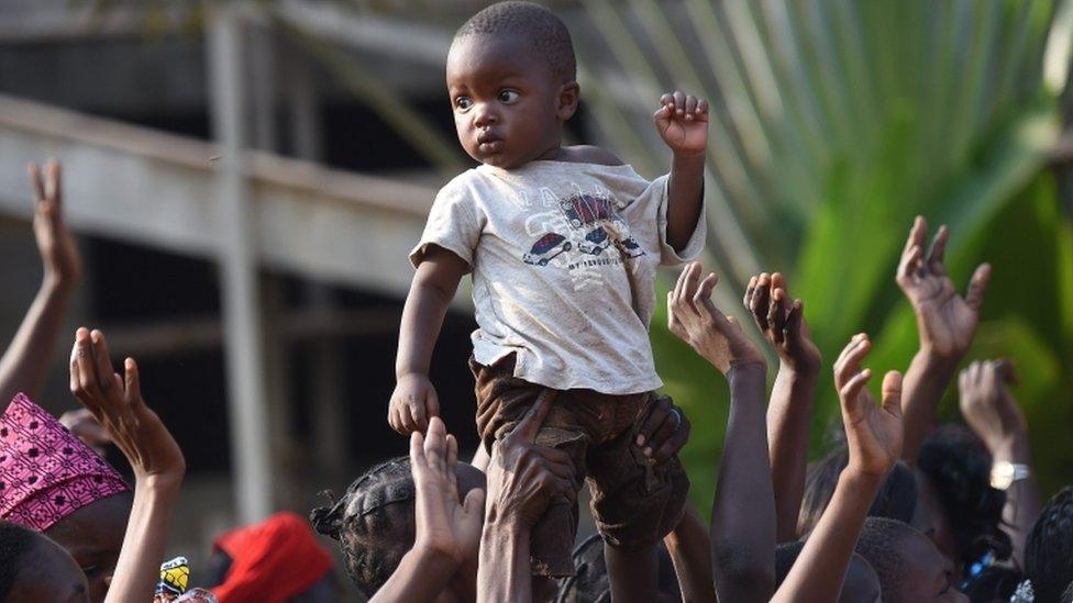 A boy is lifted by her mother at the arival of Pope Francis, at a meeting with evangelical communities at the evangelical theological school in Bangui, Central African Republic