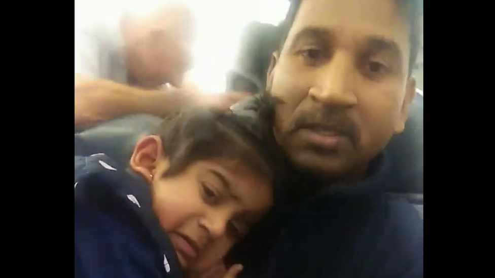 A video still of Nadesalingam holding Tharunicaa on the plane