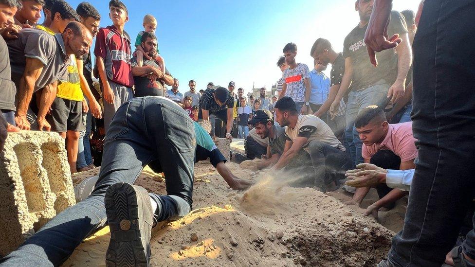 People gather around the grave of Layan al-Shaair