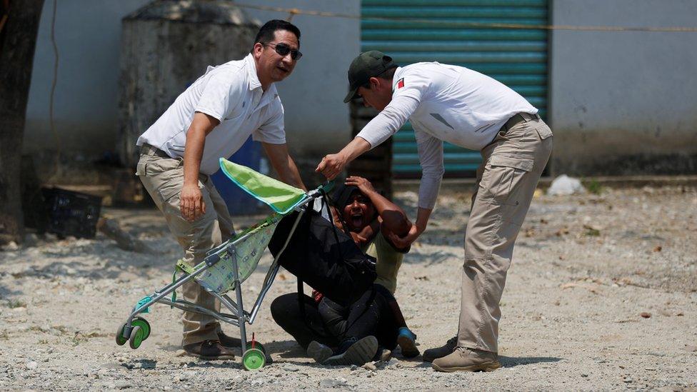 Mexican immigration officers try to detain a Central American migrant woman during an immigration raid