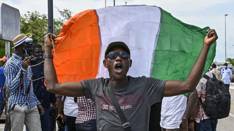 A man holds an Ivorian flag during a welcoming ceremony for several supporters of Ivorian former president Laurent Gbagbo upon their arrival in Abidjan at the end of ten years of exile in Ghana