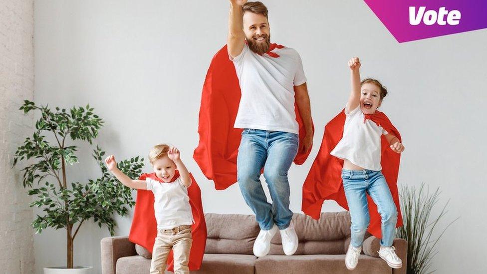 dad and two children jump in air with superhero capes