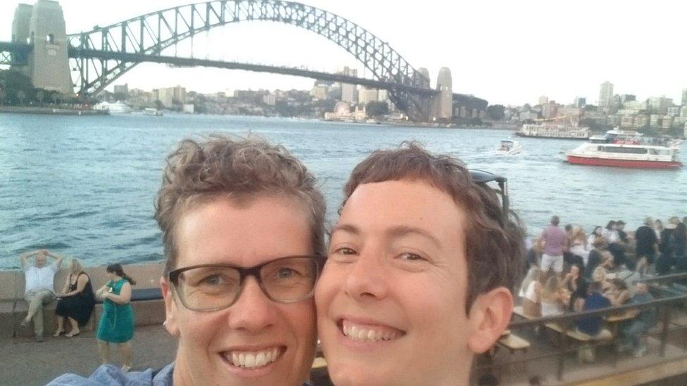 Olivia Hogarth and her partner smiling in front of the Sydney Harbour Bridge