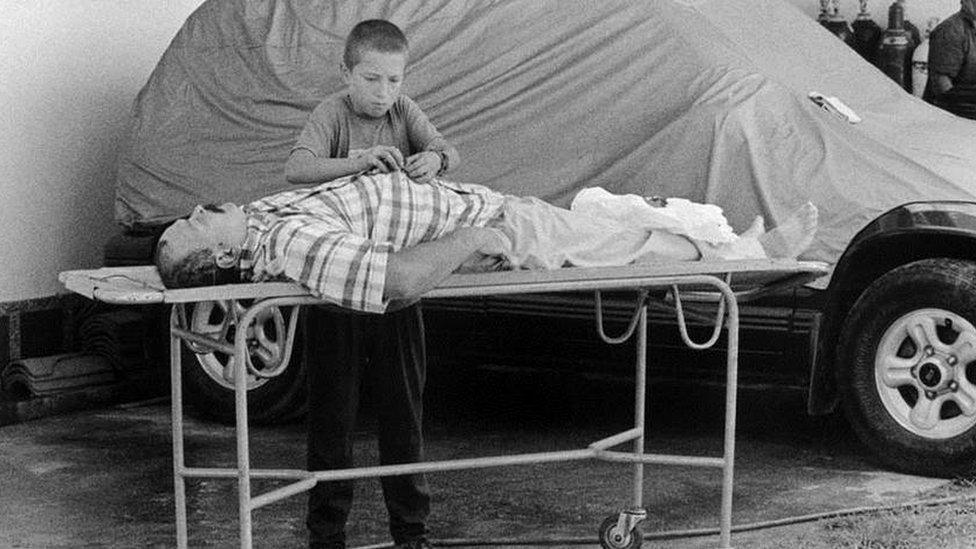 Boy fastening shirt of his dead father, who was killed by paramilitaries in San Carlos in October 1998