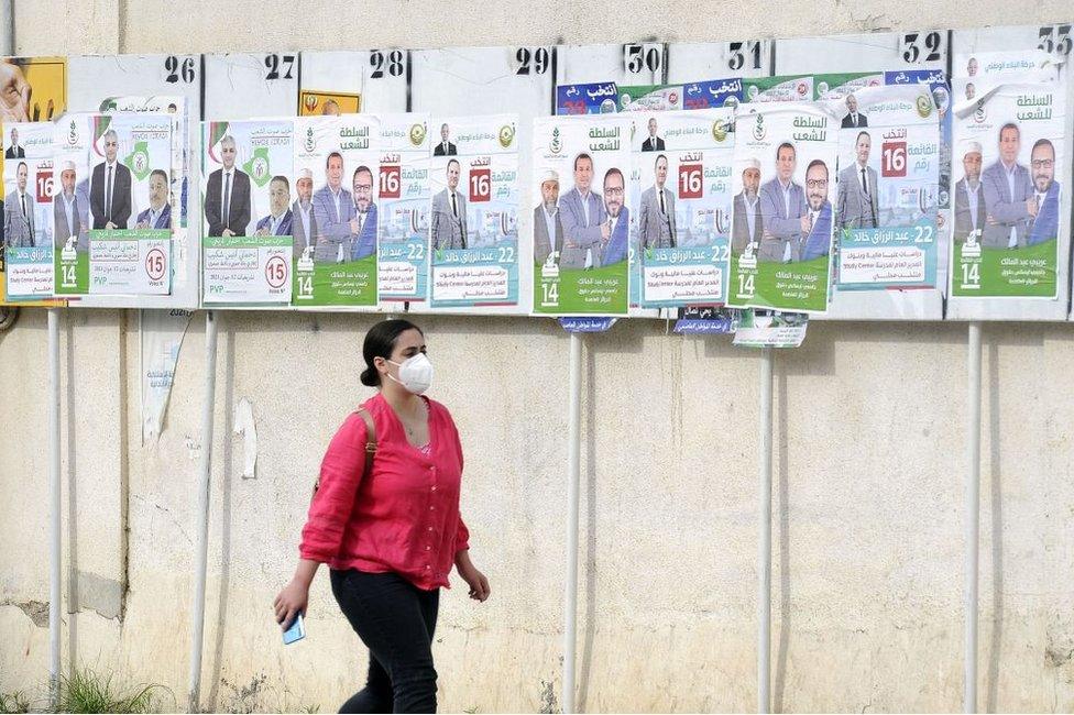 A woman walks past the political adverts in Algers, Algeria, on 8 June.