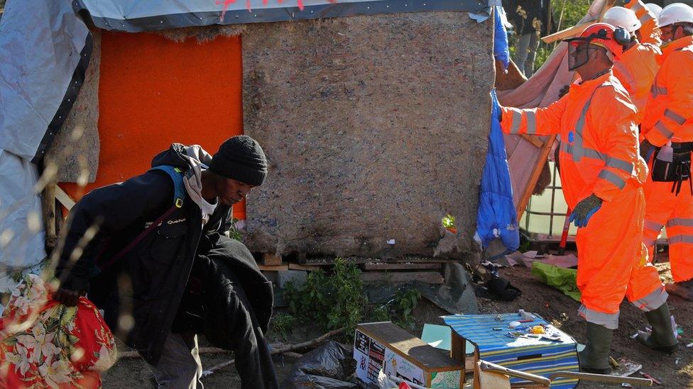 Workers pulling down a structure at the migrant camp in Calais