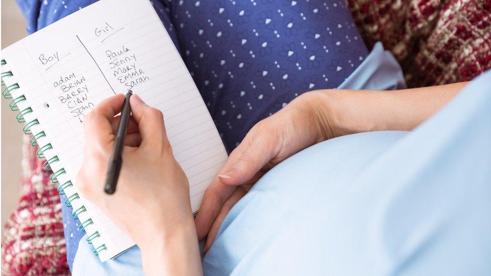 pregnant woman holding page with list of baby names