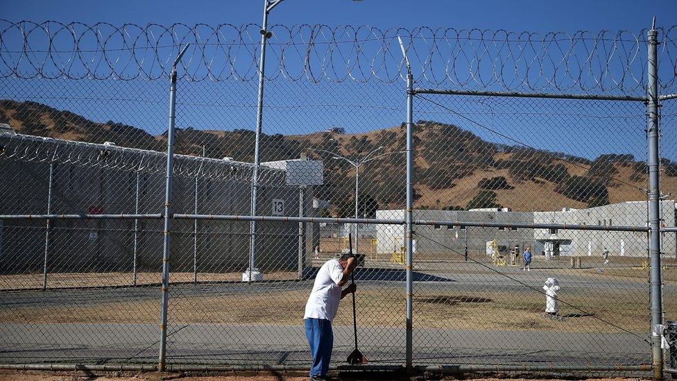 A California State Prison-Solano inmate uses a hand tool to pack decomposed granite while installing a drought-tolerant garden in the prison yard on October 19, 2015 in Vacaville, California