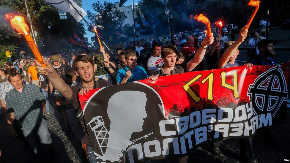 Members and supporters of Right Sector and other ultra-right political parties burn torches and carry a poster with the slogan "Freedom to political prisoners" as they march during a protest in Kiev, Ukraine, 3 July 2015