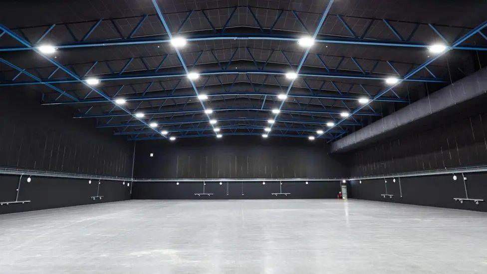 An empty studio with grey floor and bright studio lights on the ceiling