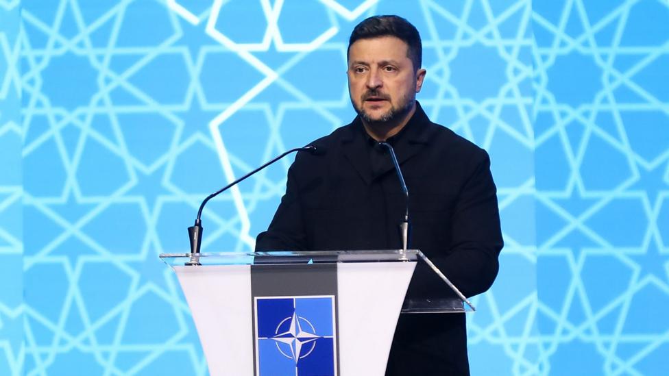 Zelensky leaves the podium holding a binder of notes