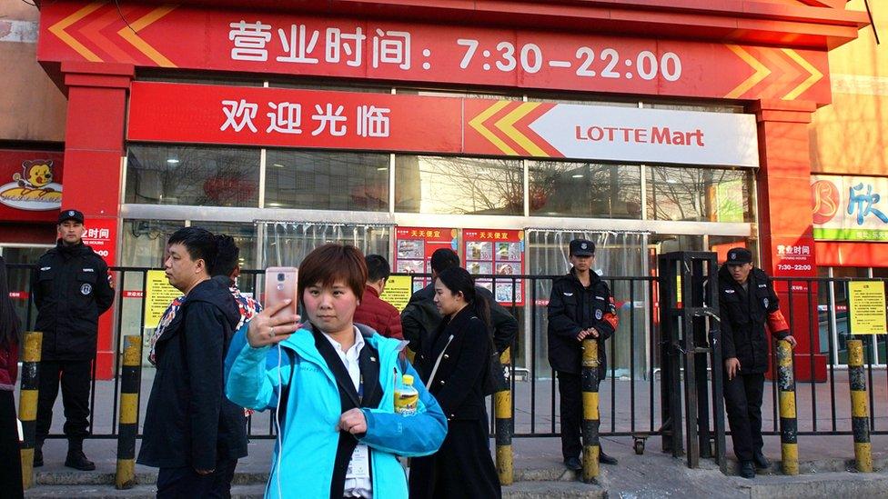 In this 13 March 2017 photo, a woman takes a selfie outside a Lotte Mart supermarket that was ordered closed by the fire department in Beijing