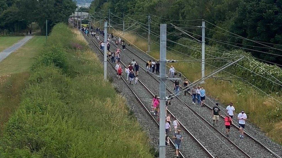 Train passengers walking along the track