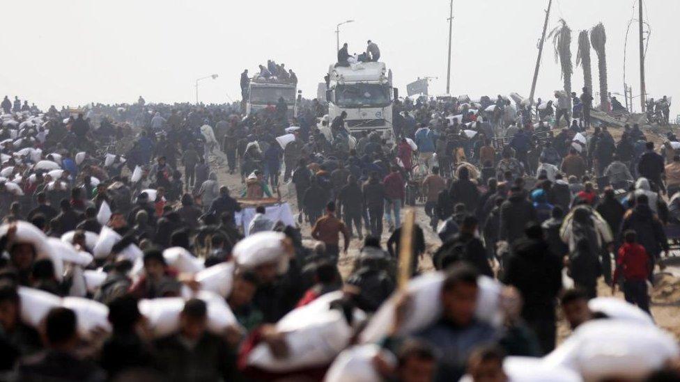 Palestinians carry bags of flour they grabbed from an aid truck near an Israeli checkpoint