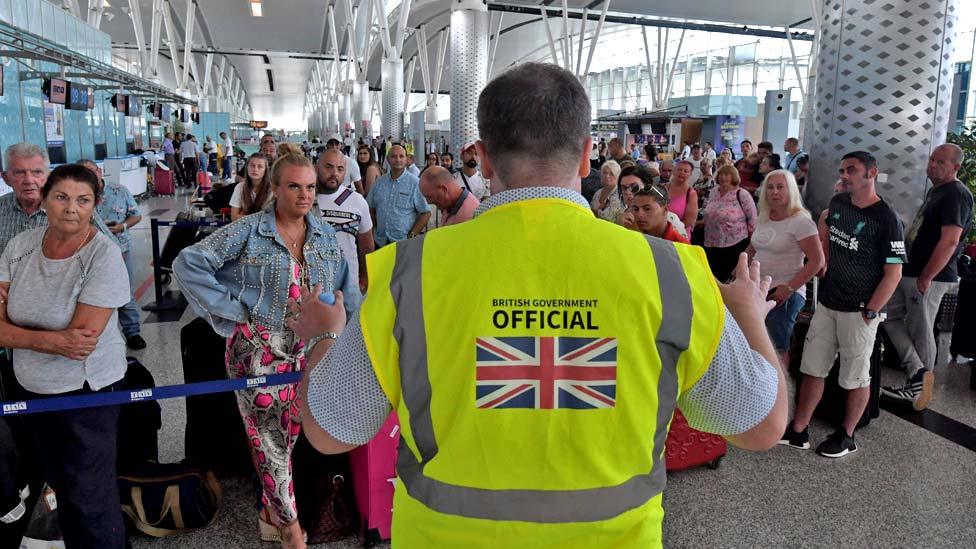 A British government official speaks to tourists, flying with Thomas Cook from Tunisia