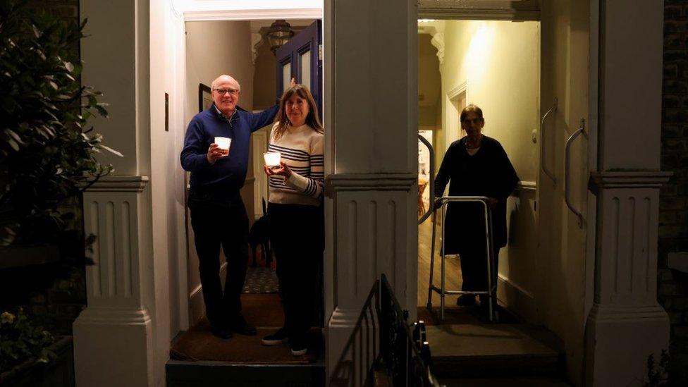 People hold candles, as part of a day of reflection to mark the anniversary of Britain"s first coronavirus lockdown, in Fulham West London