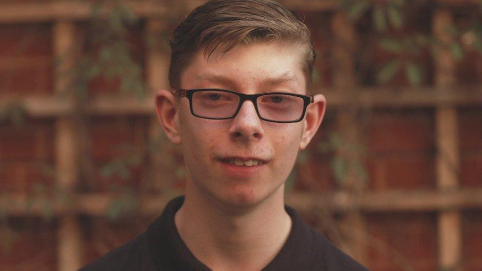 Callum a teenager against a garden trellis