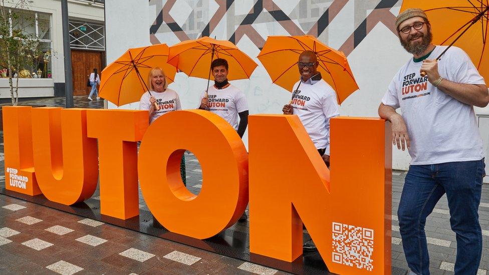 People by an orange Luton sign