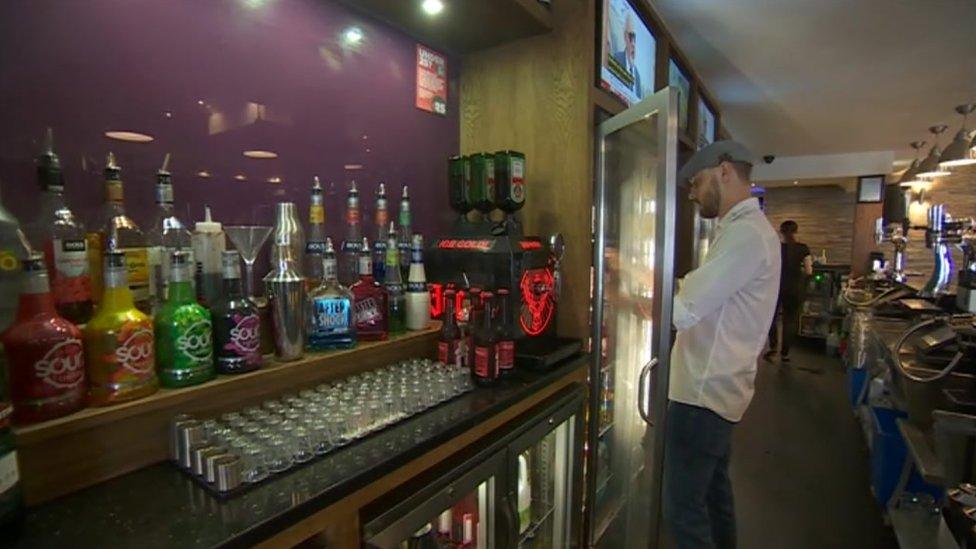 Bar manager getting a drink from fridge