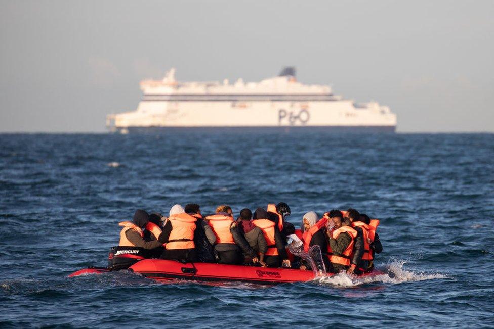 Migrants packed tightly onto a small inflatable boat bail water out as they attempt to cross the English Channel near the Dover Strait, the world's busiest shipping lane, on 7 September 2020 off the coast of Dover, England.