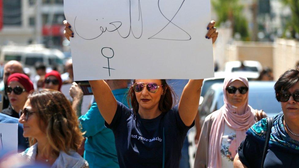 A woman holds a sign calling for an end to violence