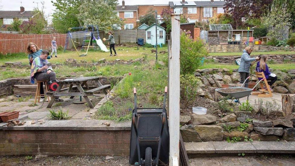 Two people cut hair in neighbouring gardens