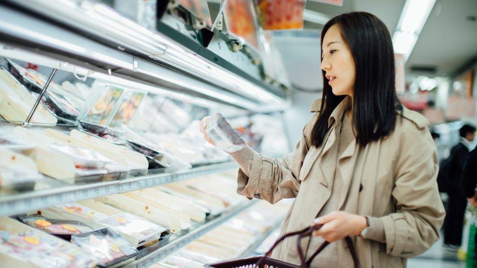 Woman checking prices in supermarket