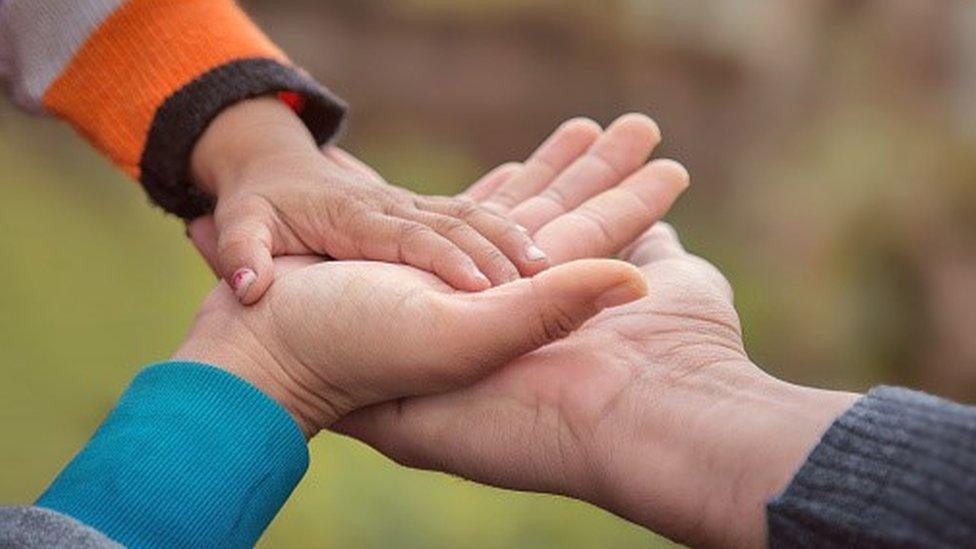 Image of child's hand holding an adult's hand