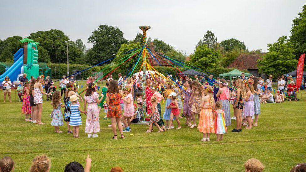 Children dance around the maypole.