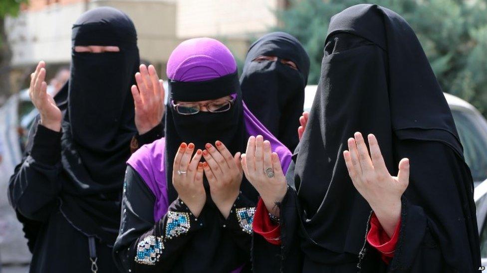 Uighur women pray after riot police used pepper spray to push back a group of Uighur protesters who try to break through a barricade outside the Chinese Embassy in Ankara